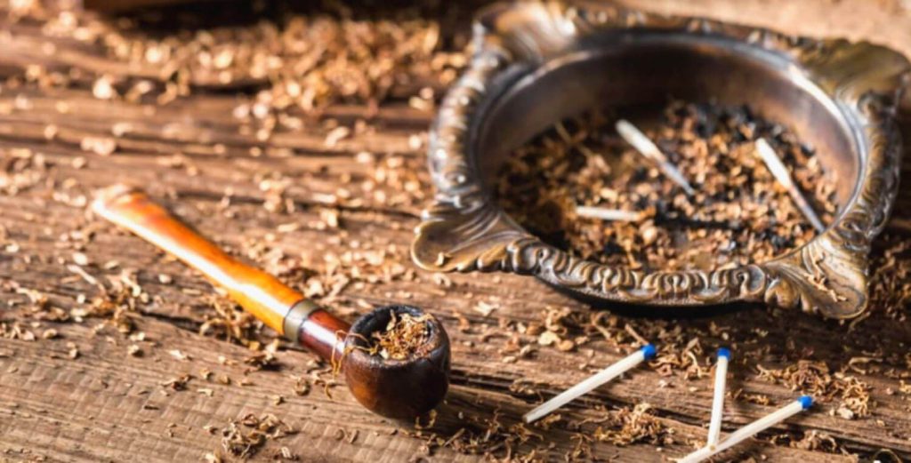 Хорошо сделанная трубка и жестянка табака Simply Latakia на деревянном столе.